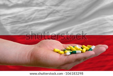 man holding capsules in front of complete wavy national flag of poland symbolizing health, medicine, cure, vitamins and healthy life