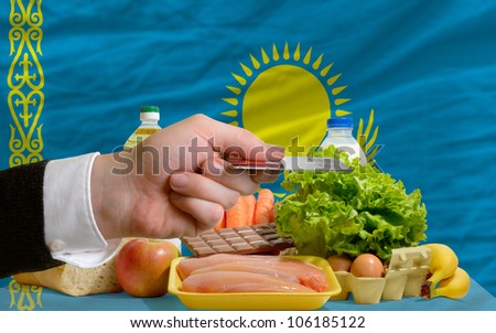 man stretching out credit card to buy food in front of complete wavy national flag of kazakhstan