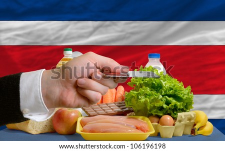 man stretching out credit card to buy food in front of complete wavy national flag of costarica