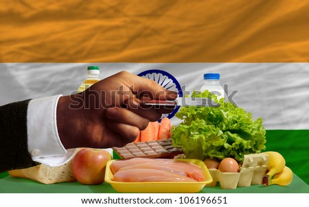 man stretching out credit card to buy food in front of complete wavy national flag of india