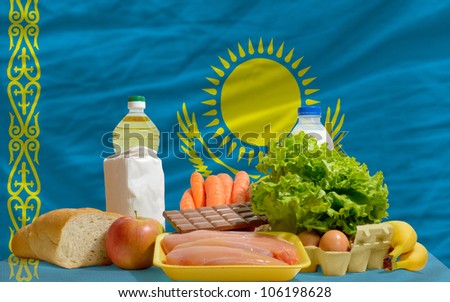 complete national flag of kazakhstan covers whole frame, waved, crunched and very natural looking. In front plan are fundamental food ingredients for consumers, symbolizing consumerism