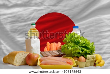 complete national flag of japan covers whole frame, waved, crunched and very natural looking. In front plan are fundamental food ingredients for consumers, symbolizing consumerism