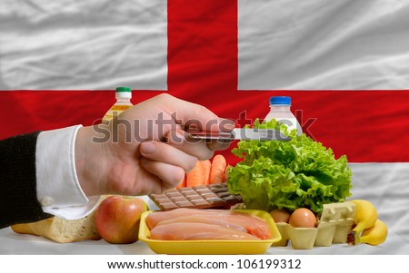 man stretching out credit card to buy food in front of complete wavy national flag of england