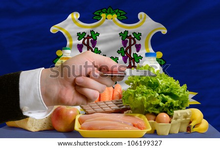 man stretching out credit card to buy food in front of complete wavy american state flag of connecticut