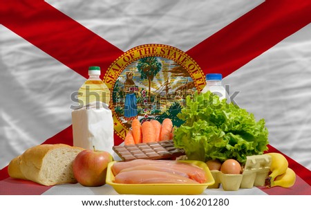 complete american state flag of florida covers whole frame, waved, crunched and very natural looking. In front plan are fundamental food ingredients for consumers, symbolizing consumerism
