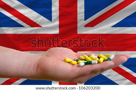 man holding capsules in front of complete wavy national flag of ik symbolizing health, medicine, cure, vitamins and healthy life