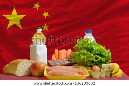 complete national flag of china covers whole frame, waved, crunched and very natural looking. In front plan are fundamental food ingredients for consumers, symbolizing consumerism
