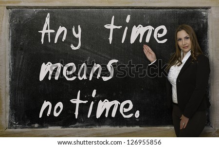 Successful, beautiful and confident woman showing Any time means no time on blackboard