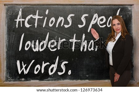 Successful, beautiful and confident woman showing Actions speak louder than words on blackboard