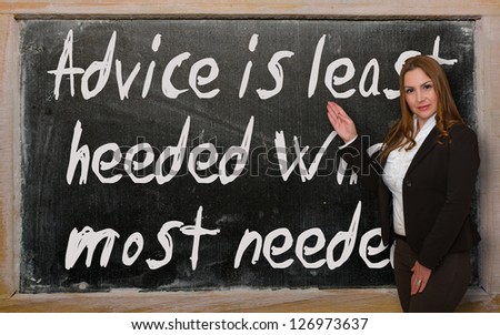 Successful, beautiful and confident woman showing Advice is least heeded when most needed on blackboard