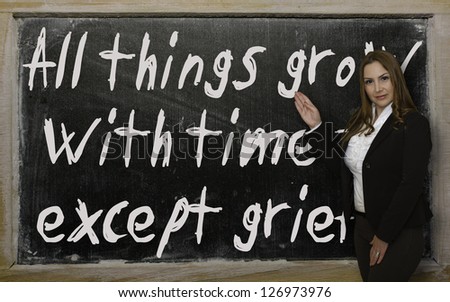 Successful, beautiful and confident woman showing All things grow with time - except grief on blackboard