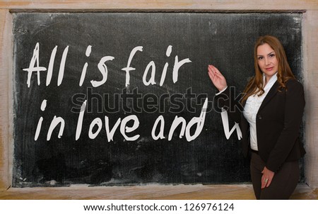 Successful, beautiful and confident woman showing All is fair in love and war on blackboard