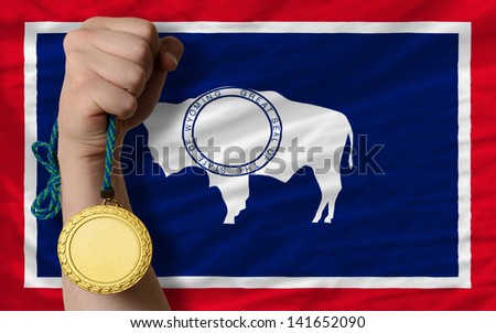 Winner holding gold medal for sport and flag of us state of wyoming