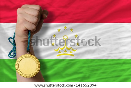 Winner holding gold medal for sport and national flag of tajikistan