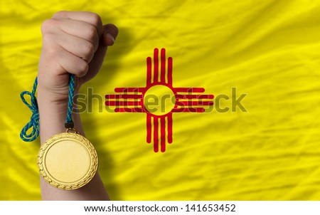 Winner holding gold medal for sport and flag of us state of new mexico