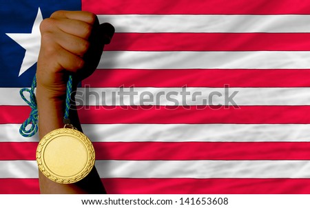 Winner holding gold medal for sport and national flag of liberia