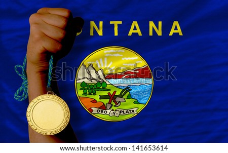 Winner holding gold medal for sport and flag of us state of montana