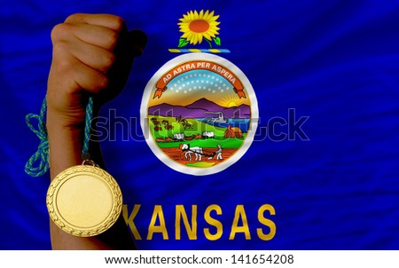 Winner holding gold medal for sport and flag of us state of kansas