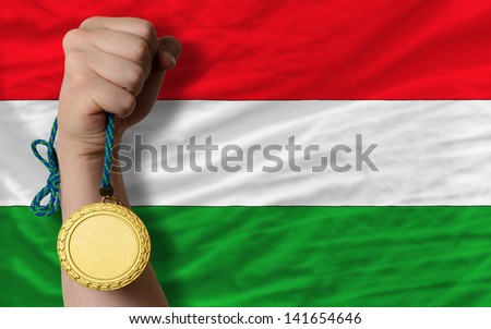 Winner holding gold medal for sport and national flag of hungary