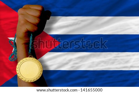 Winner holding gold medal for sport and national flag of cuba