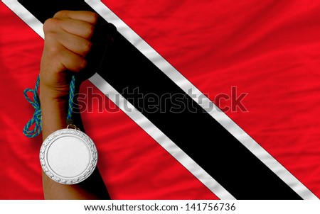Holding silver medal for sport and national flag of trinidad tobago