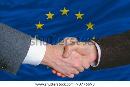 two businessmen shaking hands after good business investment  agreement in europe, in front of flag