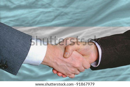 two businessmen shaking hands after good business investment  agreement in argentina, in front of flag