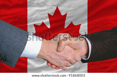 businessmen handshake after good deal in front of canada flag