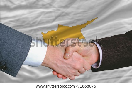 two businessmen shaking hands after good business investment  agreement in cyprus, in front of flag