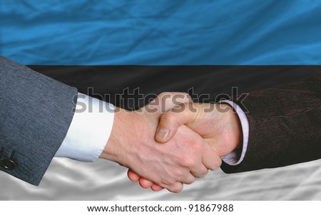two businessmen shaking hands after good business investment  agreement in estonia, in front of flag