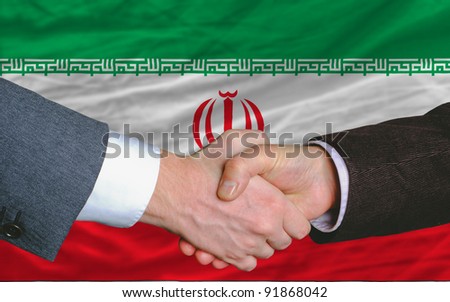 two businessmen shaking hands after good business investment  agreement in iran, in front of flag