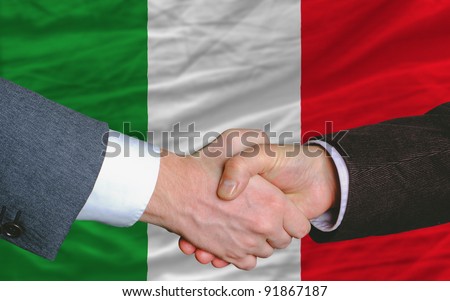 two businessmen shaking hands after good business investment  agreement in italy, in front of flag