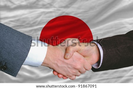 two businessmen shaking hands after good business investment  agreement in japan, in front of flag