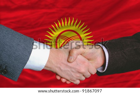 two businessmen shaking hands after good business investment  agreement in kyrghyzstan, in front of flag