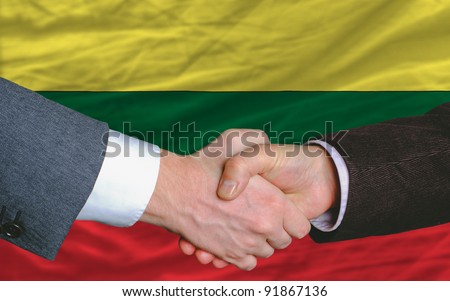 two businessmen shaking hands after good business investment  agreement in lithuania, in front of flag