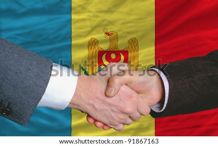 two businessmen shaking hands after good business investment  agreement in moldova, in front of flag