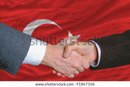 two businessmen shaking hands after good business investment  agreement in turkey, in front of flag