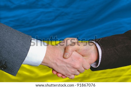two businessmen shaking hands after good business investment  agreement in ukraine, in front of flag