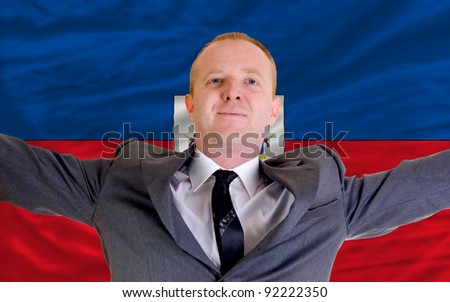 joyful investor spreading arms after good business investment in haiti, in front of flag