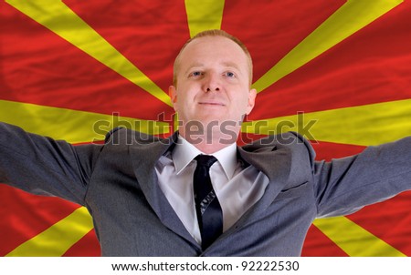 joyful investor spreading arms after good business investment in macedonia, in front of flag