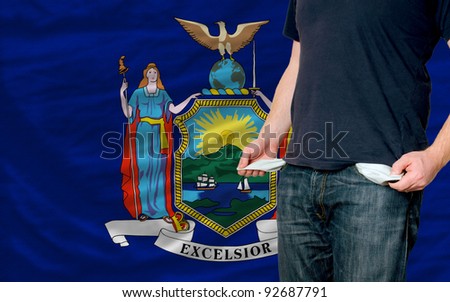 poor man showing empty pockets in front of american state of new york flag
