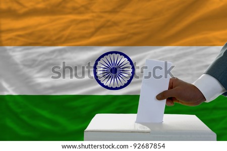 man putting ballot in a box during elections  in front of national flag of india