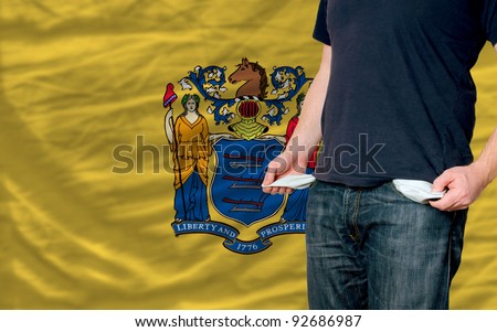 poor man showing empty pockets in front of american state of new jersey flag