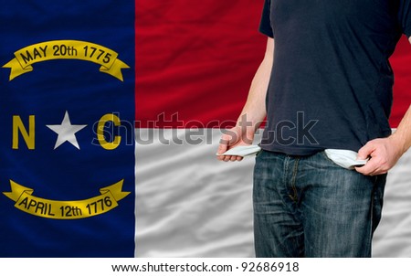 poor man showing empty pockets in front of american state of north carolina flag