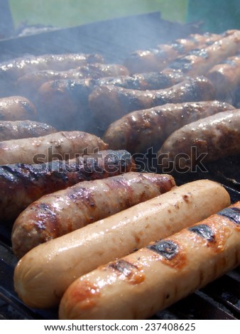 Sausages and wursts cooking on an outdoor grill, vertical