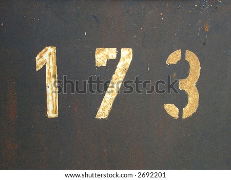 Stencil painted number 173 on a rusty plate