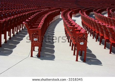 Red plastic seats in rows in an outdoor theater, side view, numbered