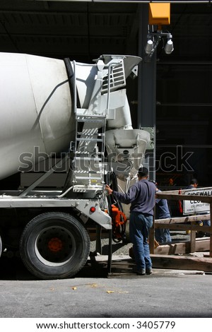 Worker and concrete mixer truck pouring cement at construction site