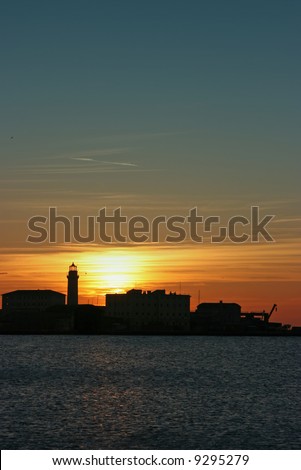Silhouette of a lighthouse at sunset in the port of Trieste, Italy