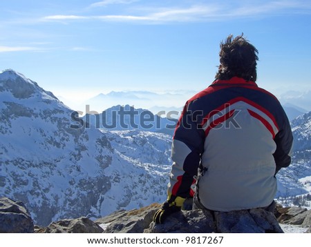Man looking over mountains top above passo Pramollo on the border between Italy and Austria